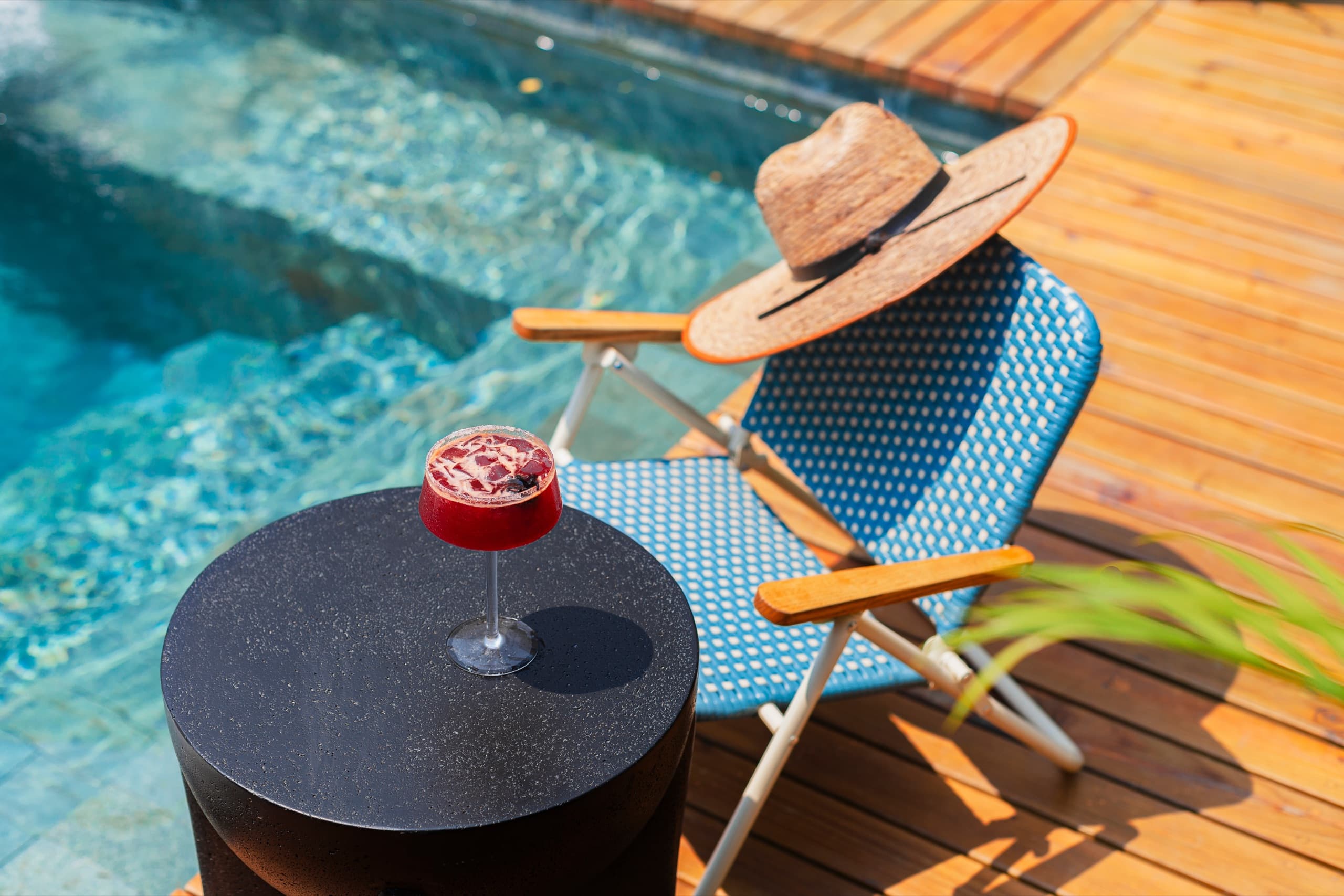 Poolside lounge chair with a sun hat and a cocktail